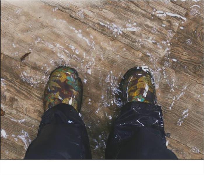 Feet with rain boots in a flooded house