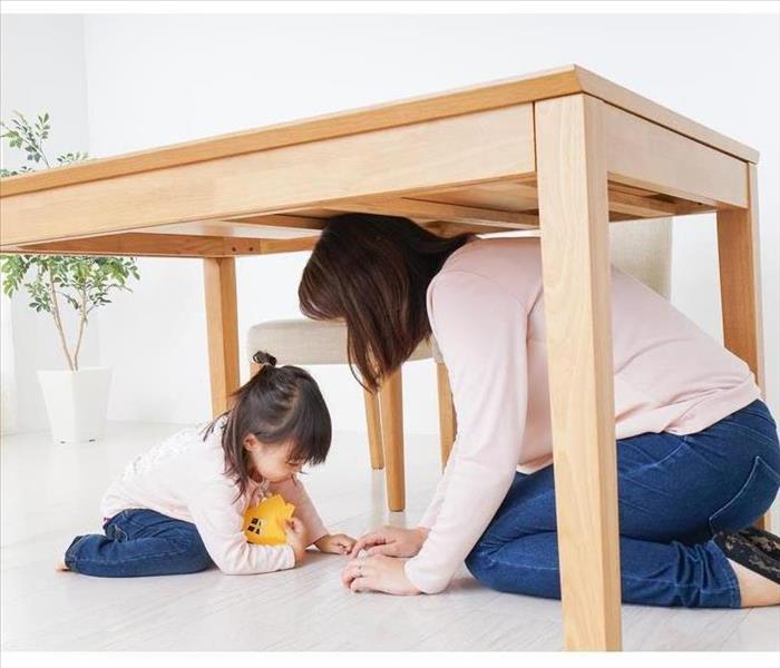 A parent and child huddling under a table